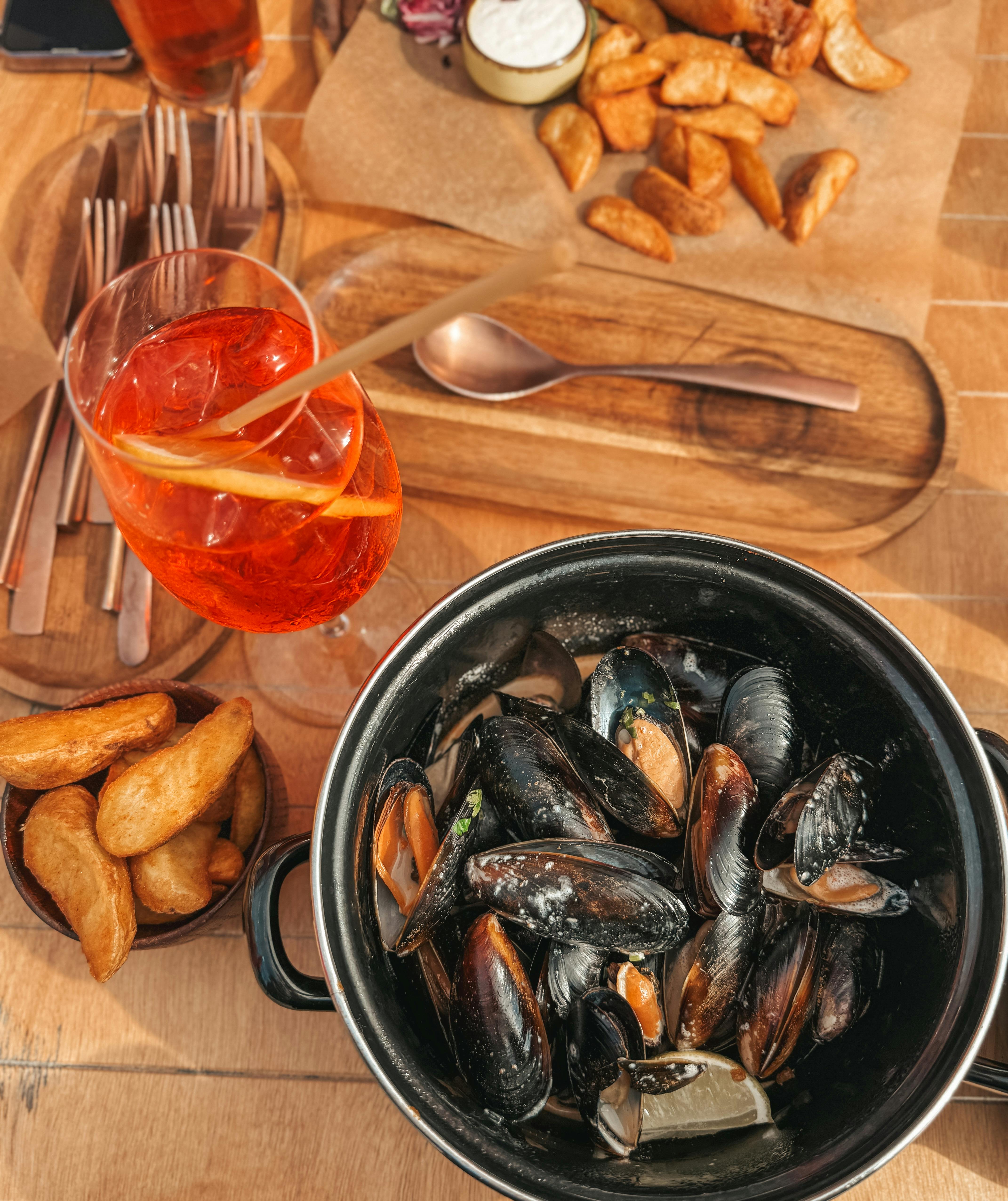 Aperol Spritz e piatti di mare disposti su tavolo di legno