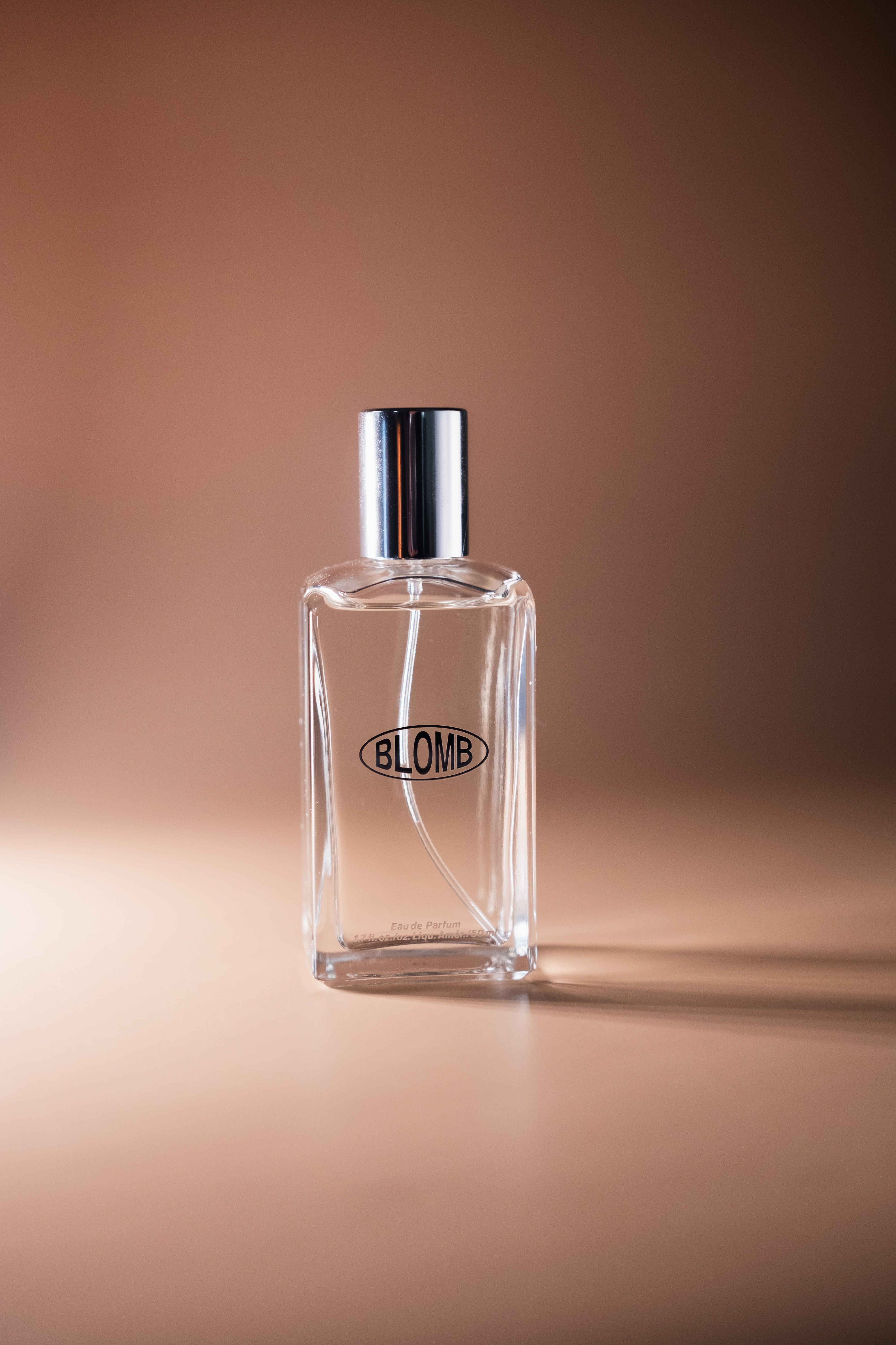 Transparent perfume bottle with elegant design on a warm-toned background, ideal for lifestyle imagery.