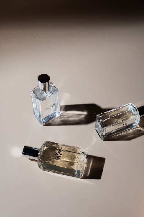 Free Three elegant perfume bottles casting shadows on a minimalist surface, captured in natural light. Stock Photo