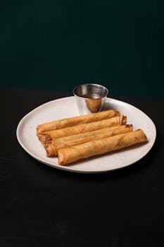 Crispy Filipino lumpia served on a plate with dipping sauce. Perfect appetizer or snack.
