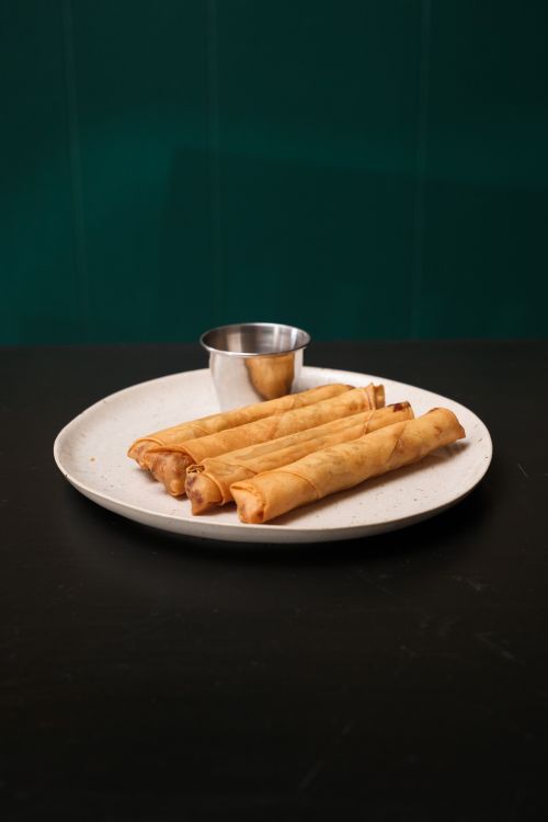 Free A plate of golden Filipino lumpia served with dipping sauce, showcasing traditional flavors. Stock Photo