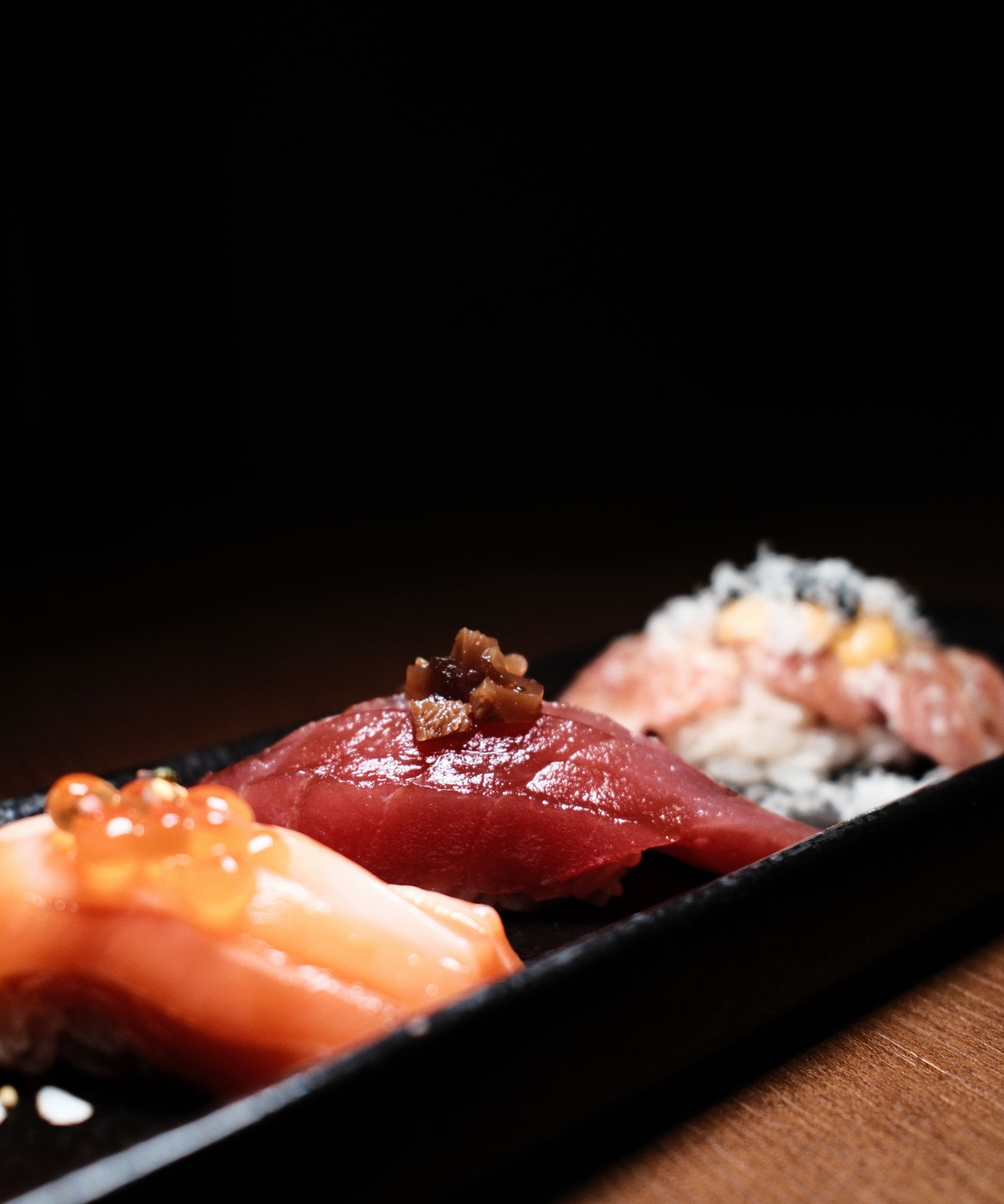 Close-up of a delicious sushi nigiri platter with fresh toppings on a black plate.