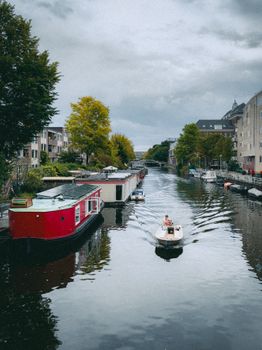 A serene view of houseboats and a small boat on an Amsterdam canal.