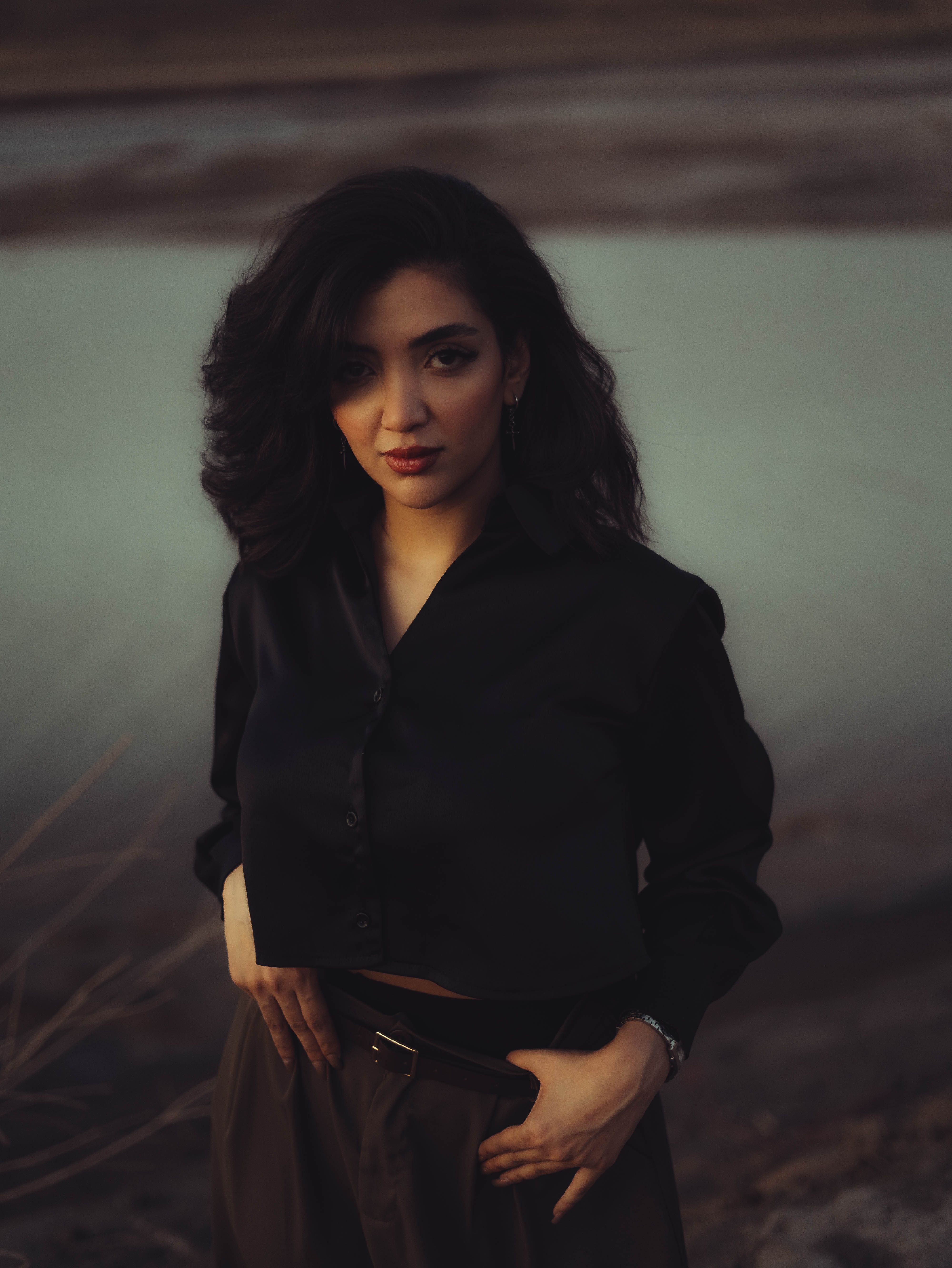Portrait of a fashionable woman outdoors at dusk, exuding confidence and style.
