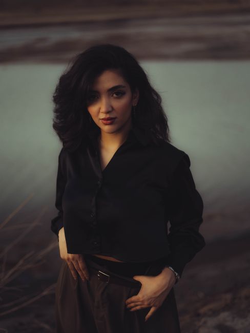 Portrait of a fashionable woman outdoors at dusk, exuding confidence and style.