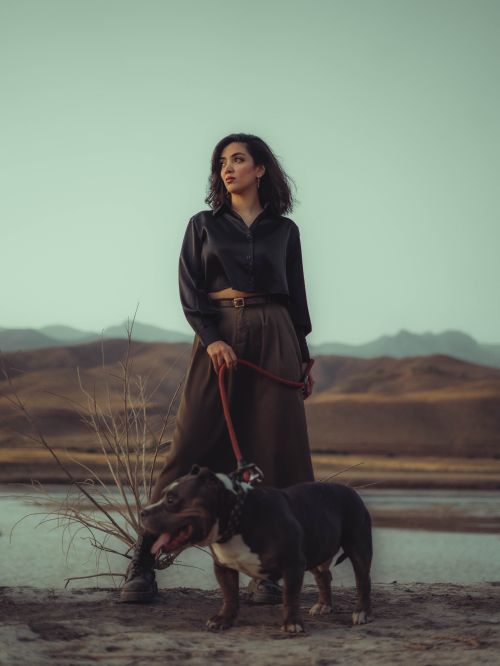 Free Stylish woman with a dog on a leash in a serene desert setting. Stock Photo