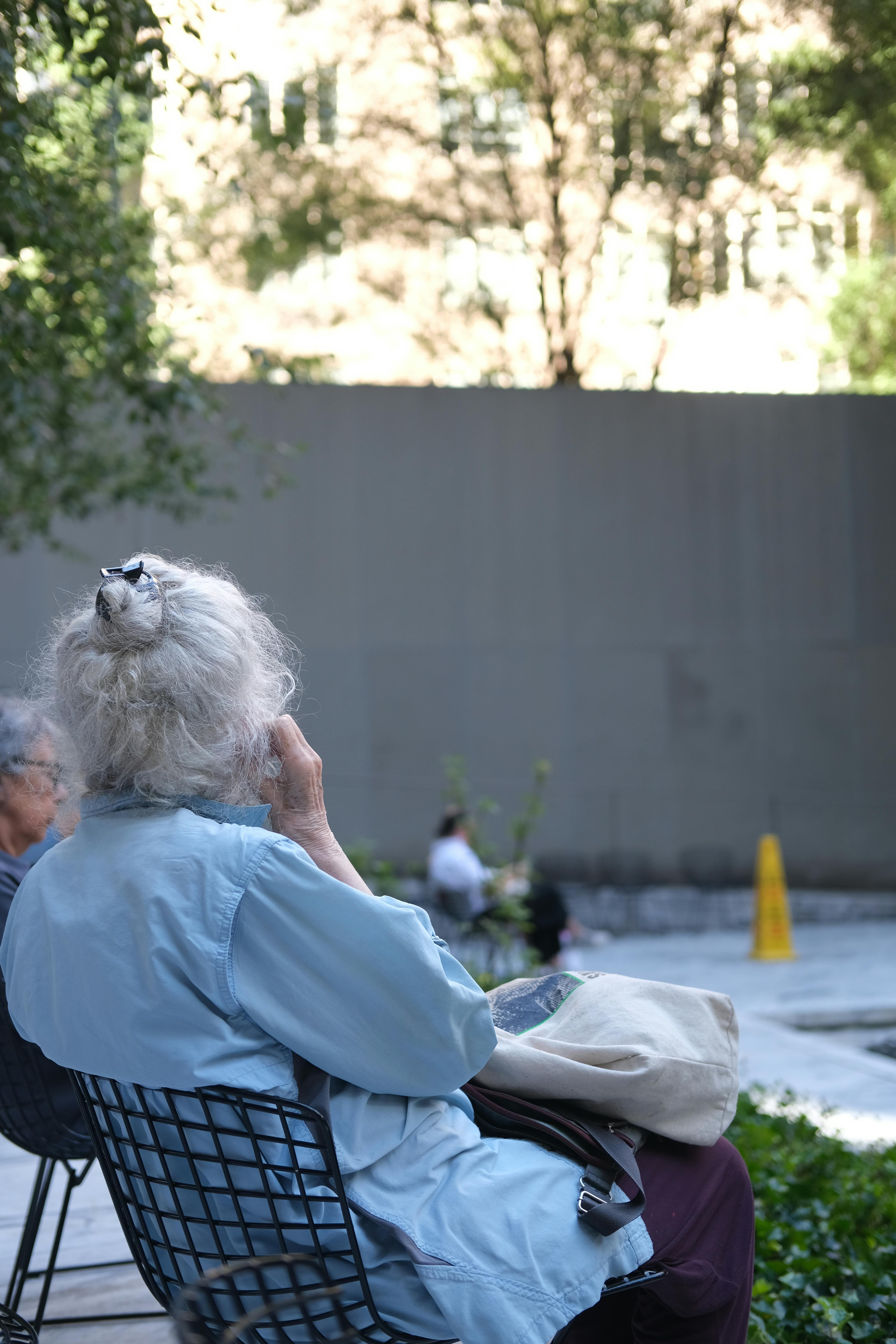 A peaceful scene with senior adults seated outdoors in a sunlit urban park.