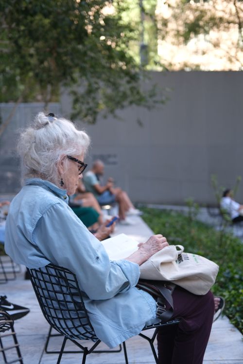 Free Elderly woman enjoying a peaceful moment reading in a serene park environment. Stock Photo