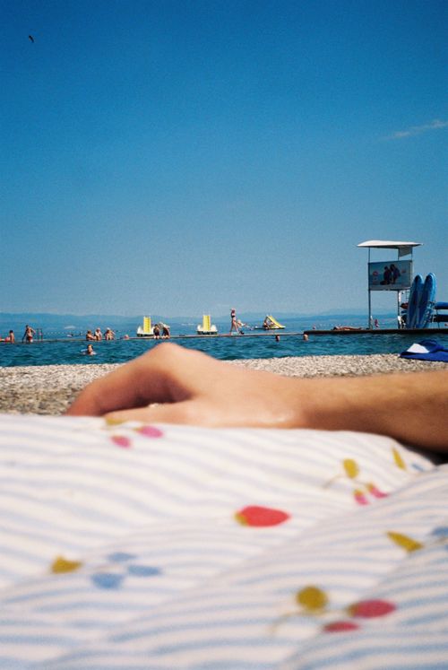 Free Serene beach scene with people enjoying the sun by the shore. Perfect summer vibes. Stock Photo