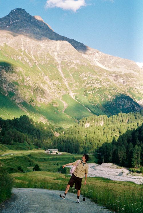 Free A hiker joyfully explores a lush mountain landscape under a bright summer sky. Stock Photo
