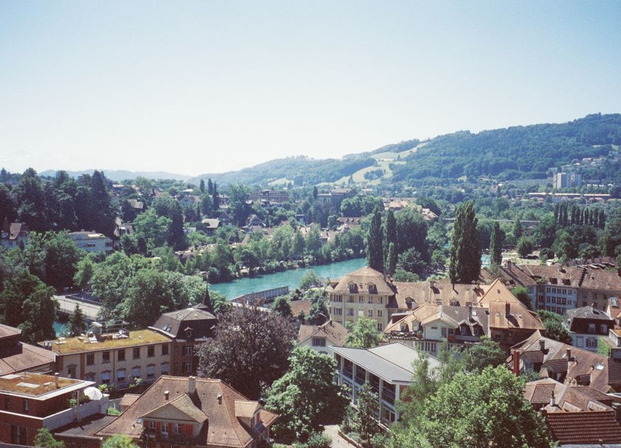 A scenic aerial view of a quaint Swiss town with lush greenery and a winding river.