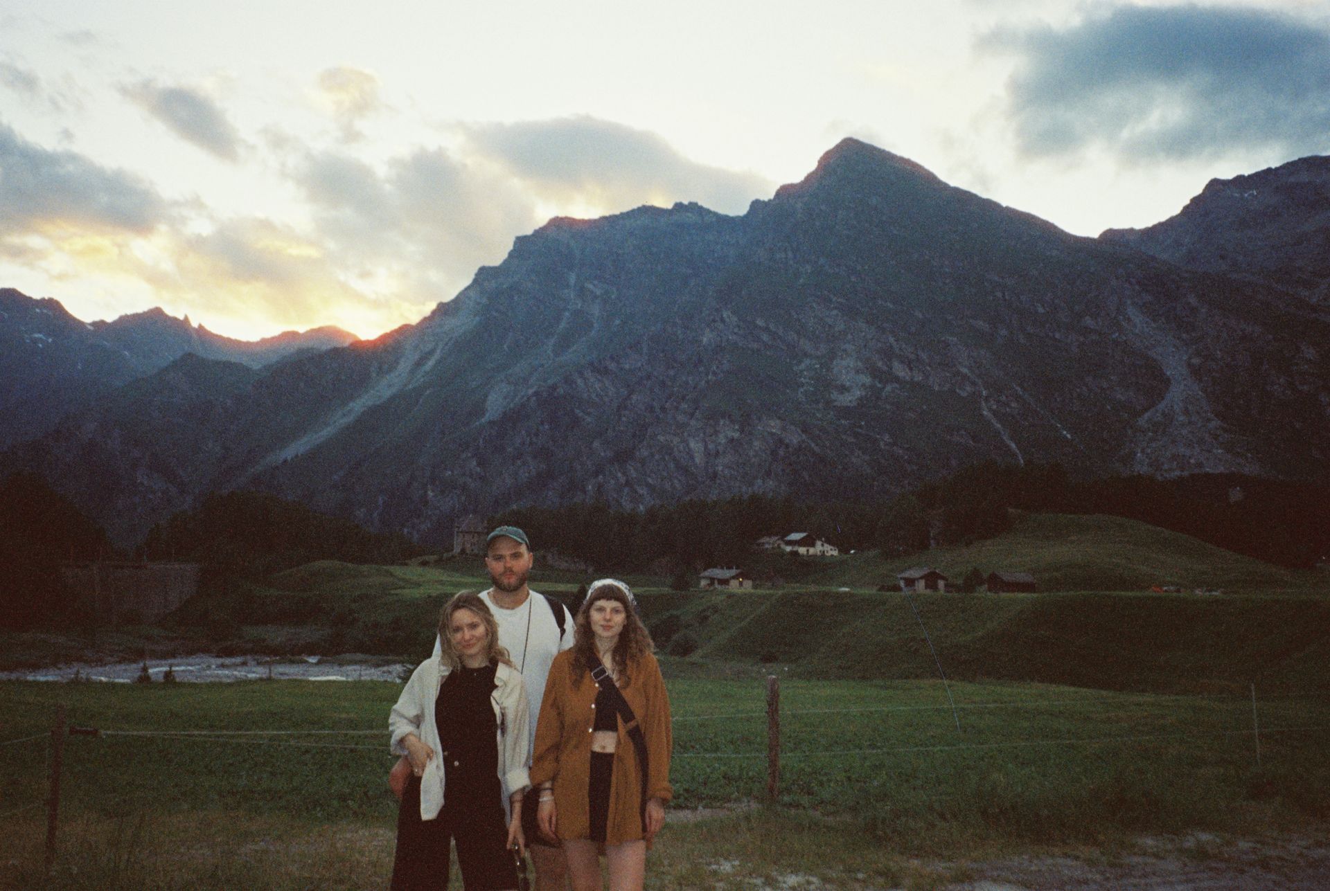 Three adults pose in a picturesque mountain landscape during sunset, showcasing the beauty of nature and adventure.