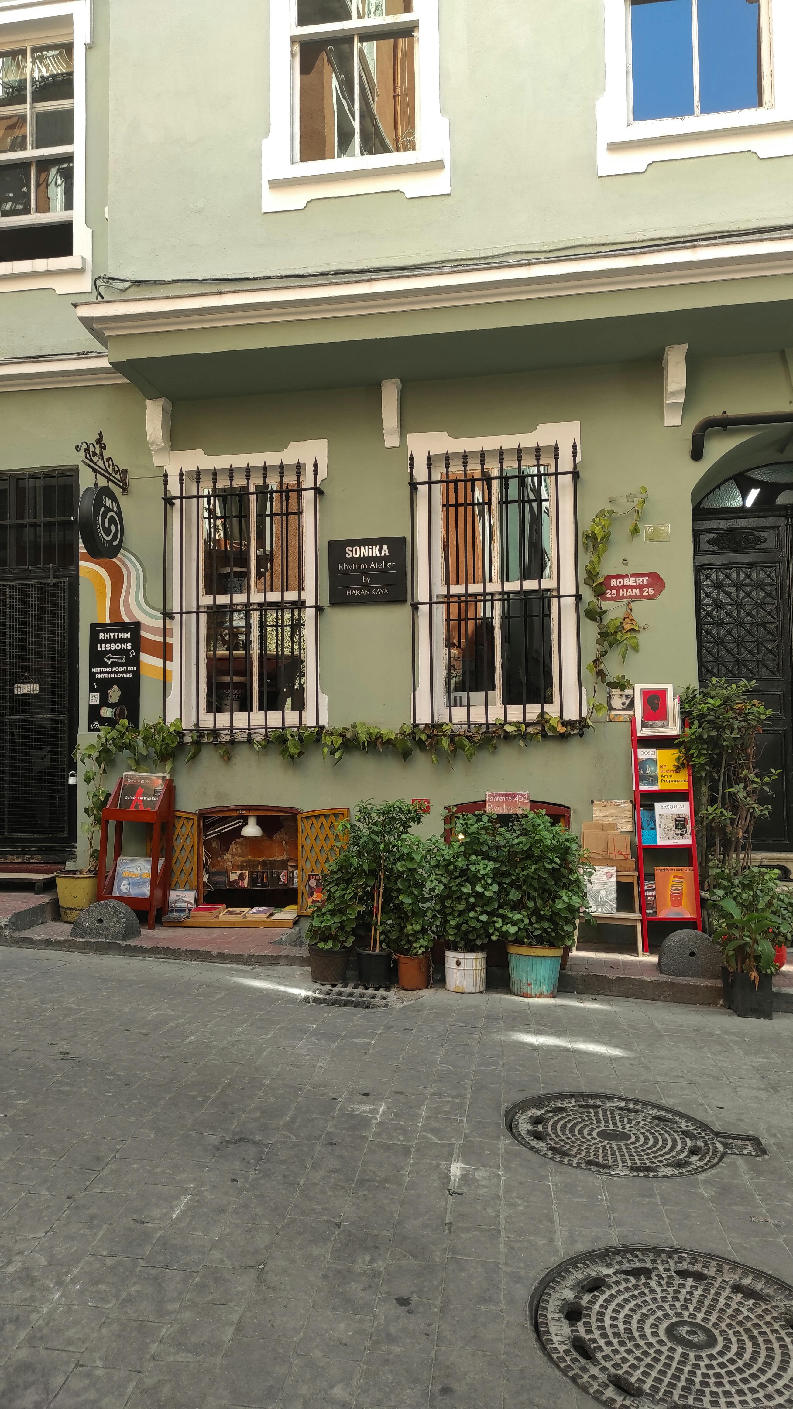 Charming outdoor view of a colorful urban café with vibrant decor and potted plants, inviting ambiance on a sunny day.