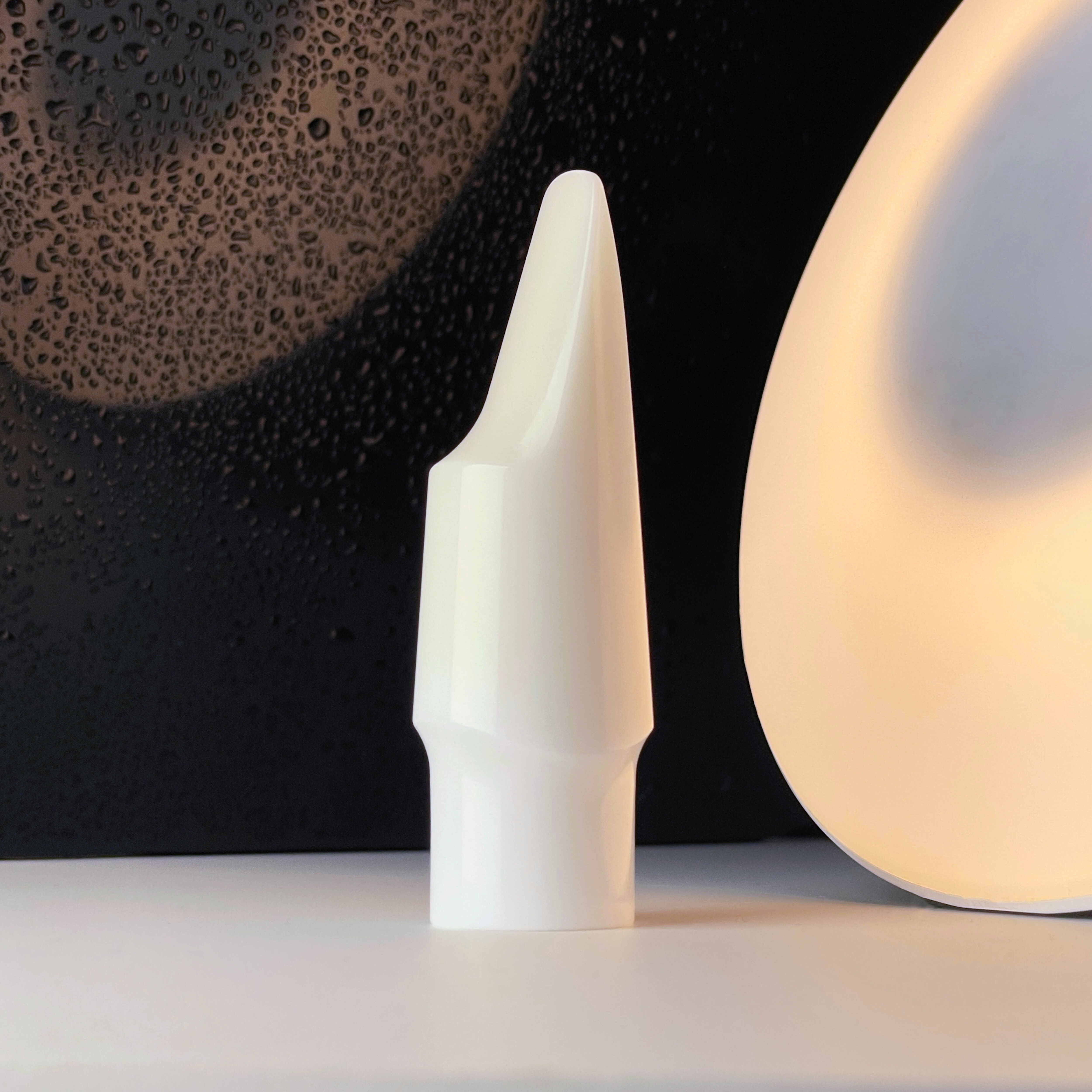 Forme céramique blanche incurvée en gros plan sur fond sombre évoquant les propriétés de l'alumine Al2O3