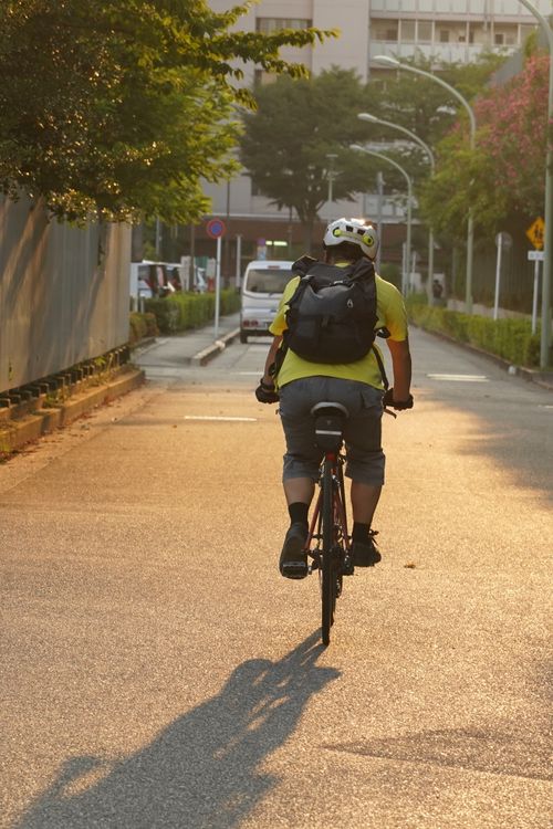 Free A cyclist rides through Ota City, Tokyo during golden hour, creating a serene urban scene. Stock Photo