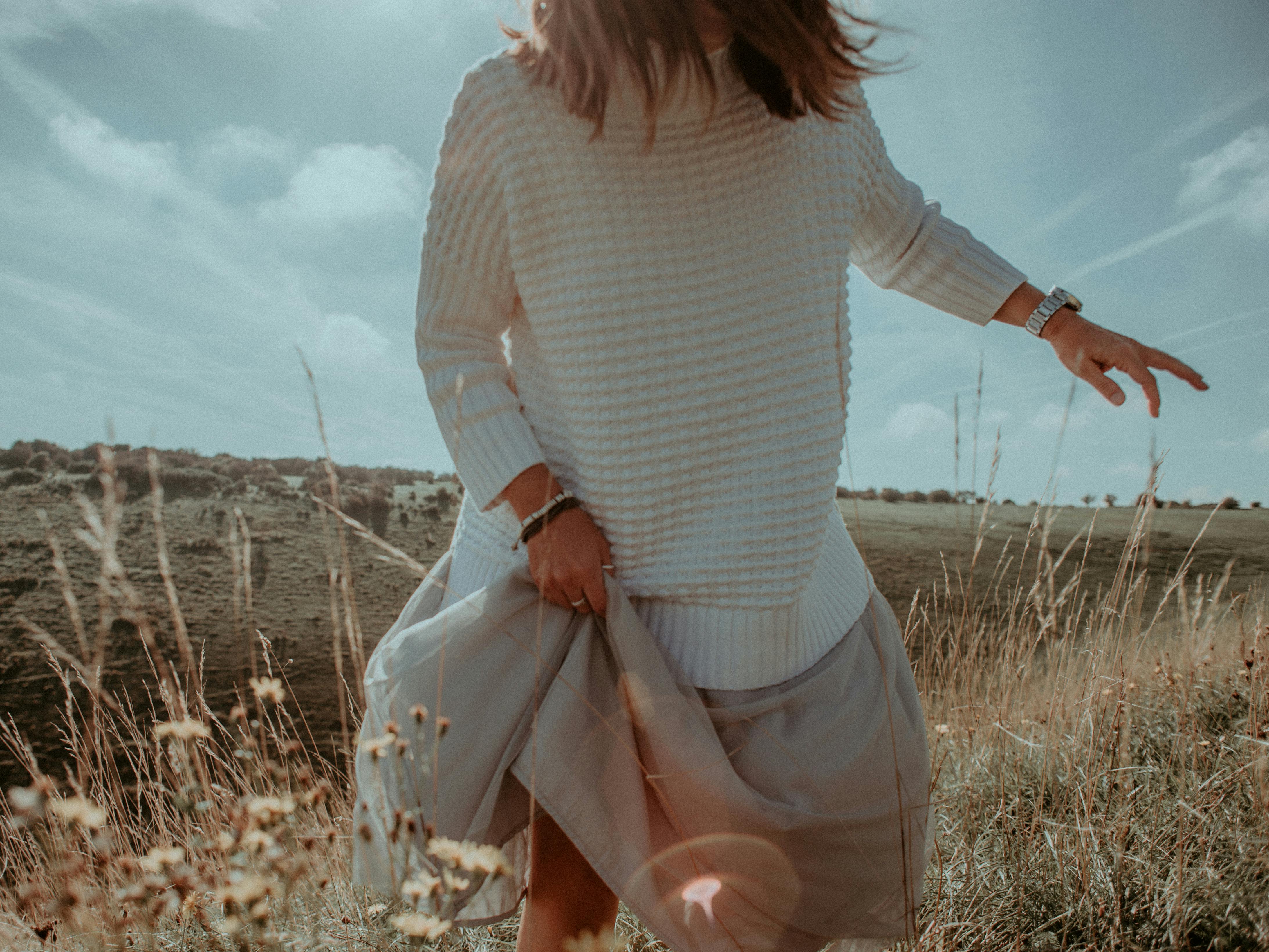 standing woman in white sweater on plant field