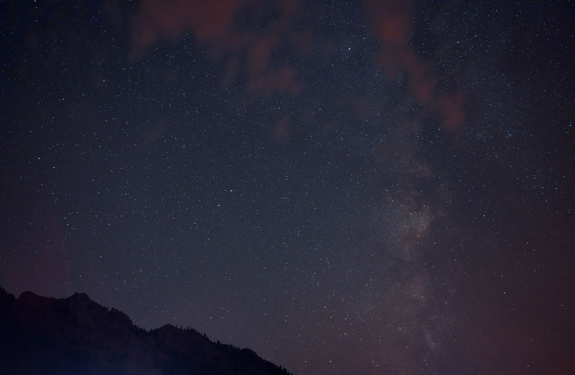 Vibrant night sky with stars and Milky Way over silhouetted mountains.