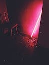 一间霓虹灯昏暗的房间里，引人注目的红光投射而出，照亮了一把孤零零的椅子和散落的碎片