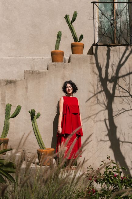 Stylish young woman in red dress by cactus garden in Purísima de Cubos, Mexico.