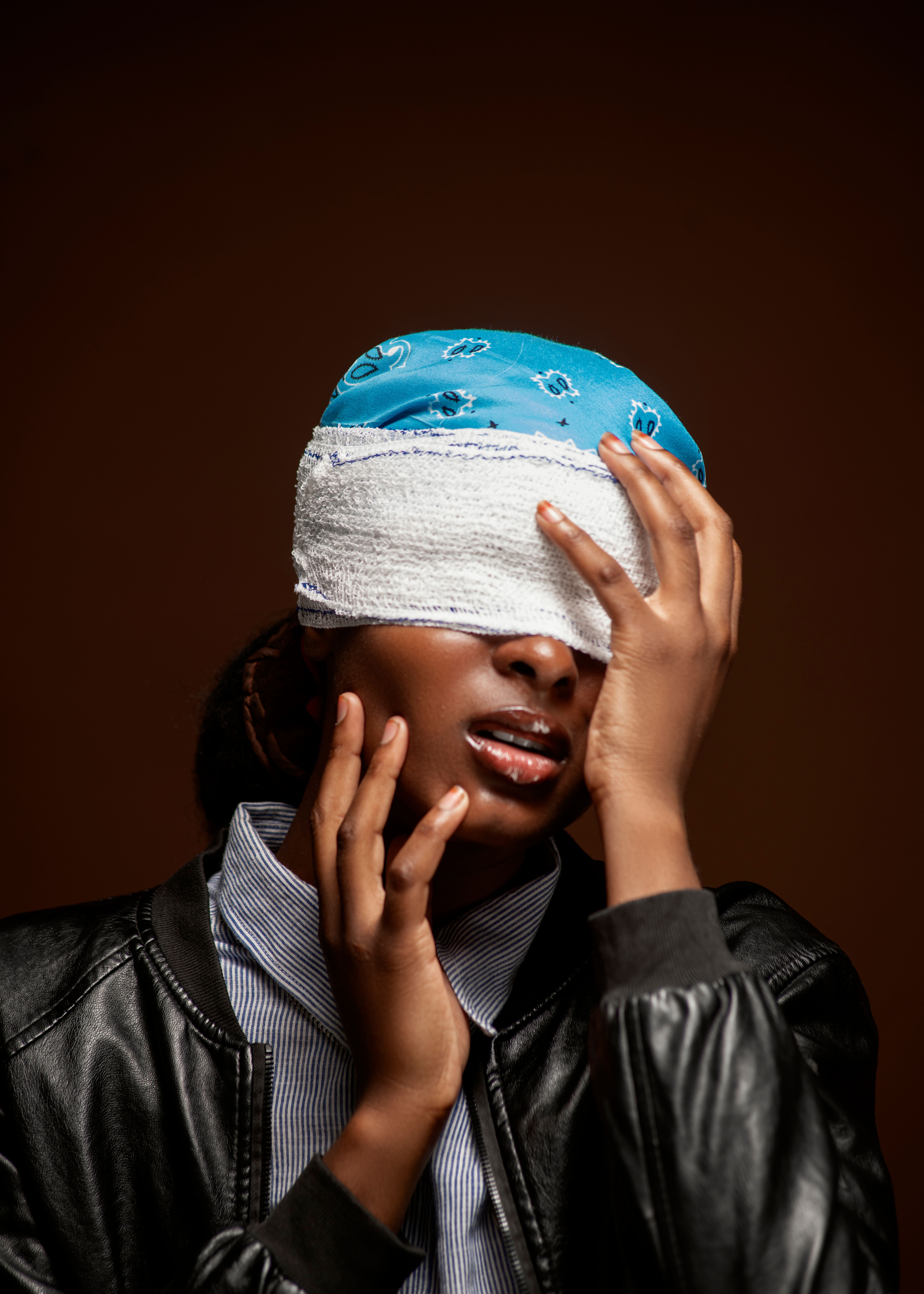 Close-up of an adult with a bandaged head and a concerned expression, isolated on a brown background.