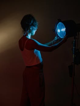 Artistic portrait of a woman adjusting studio lights, showcasing creative lighting techniques.