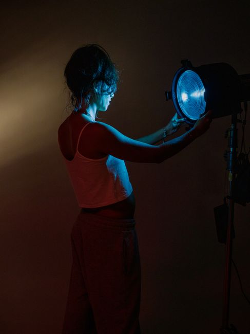 Artistic portrait of a woman adjusting studio lights, showcasing creative lighting techniques.