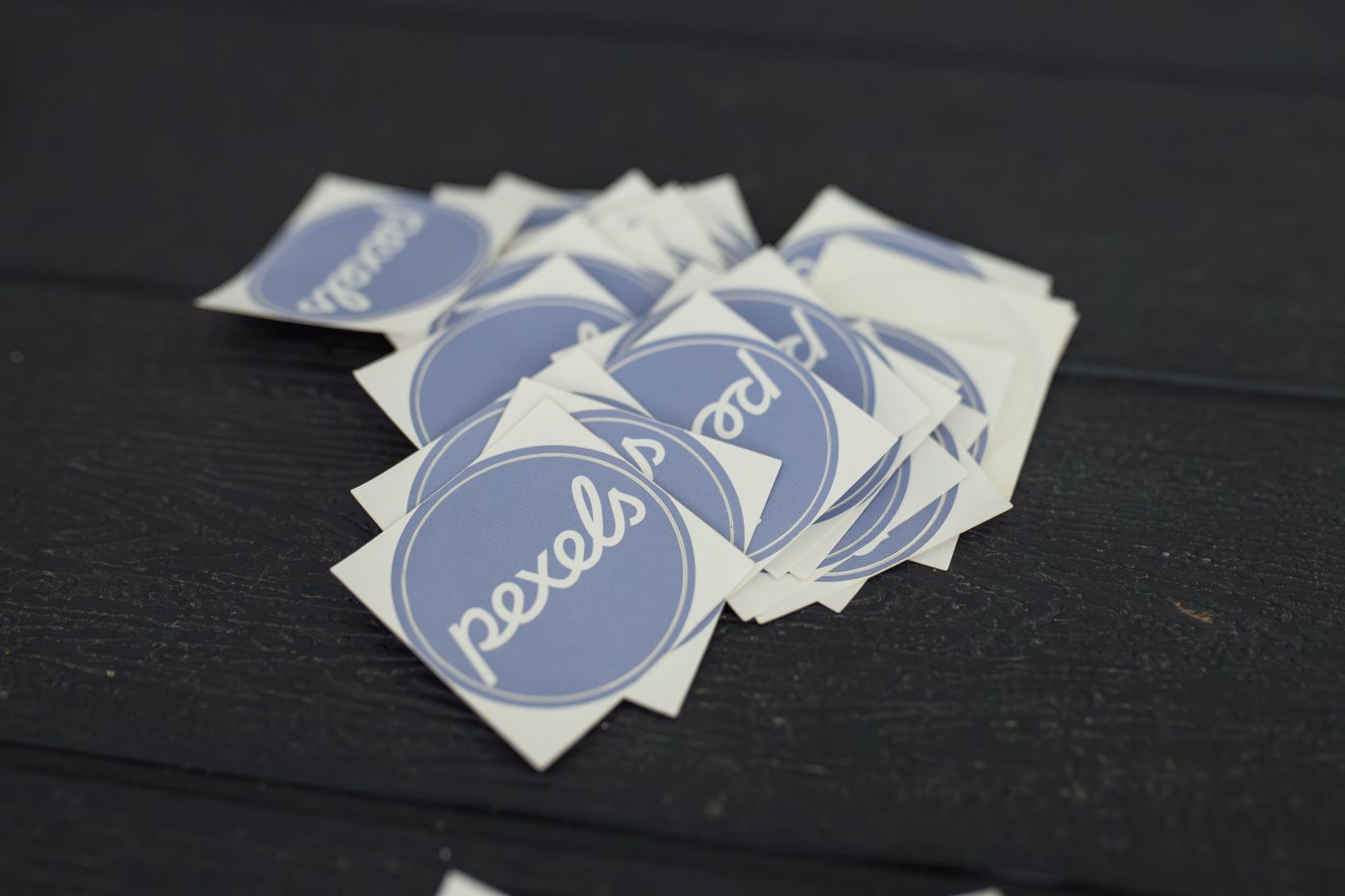 Pile of die-cut printed vinyl stickers on a dark wooden surface