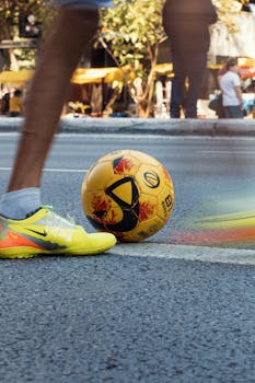 Dynamic street soccer scene featuring a player with yellow shoes and a yellow football. Action and excitement captured.