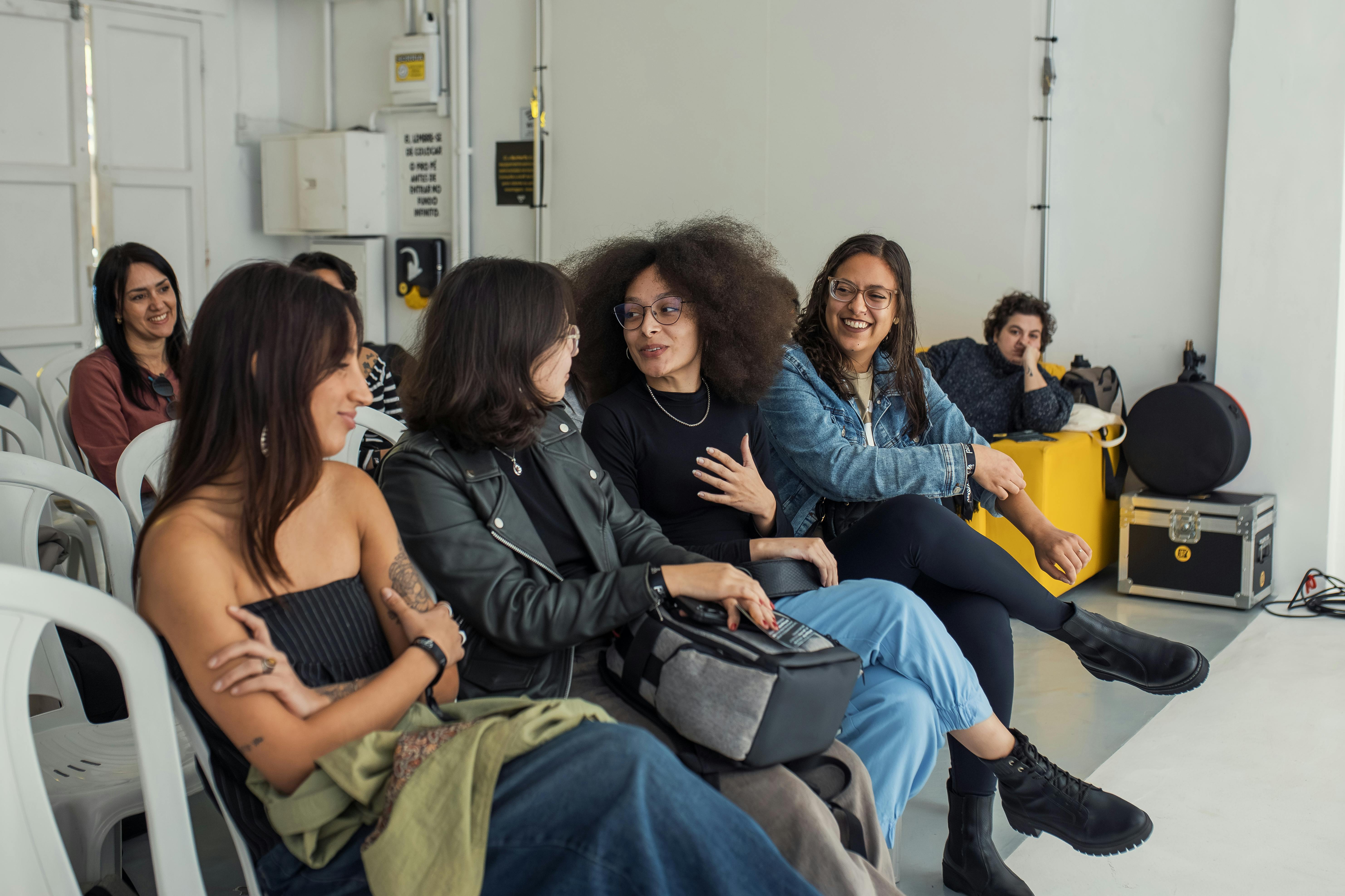 A diverse group of friends enjoying a lively conversation indoors, showcasing camaraderie and diverse fashion styles.