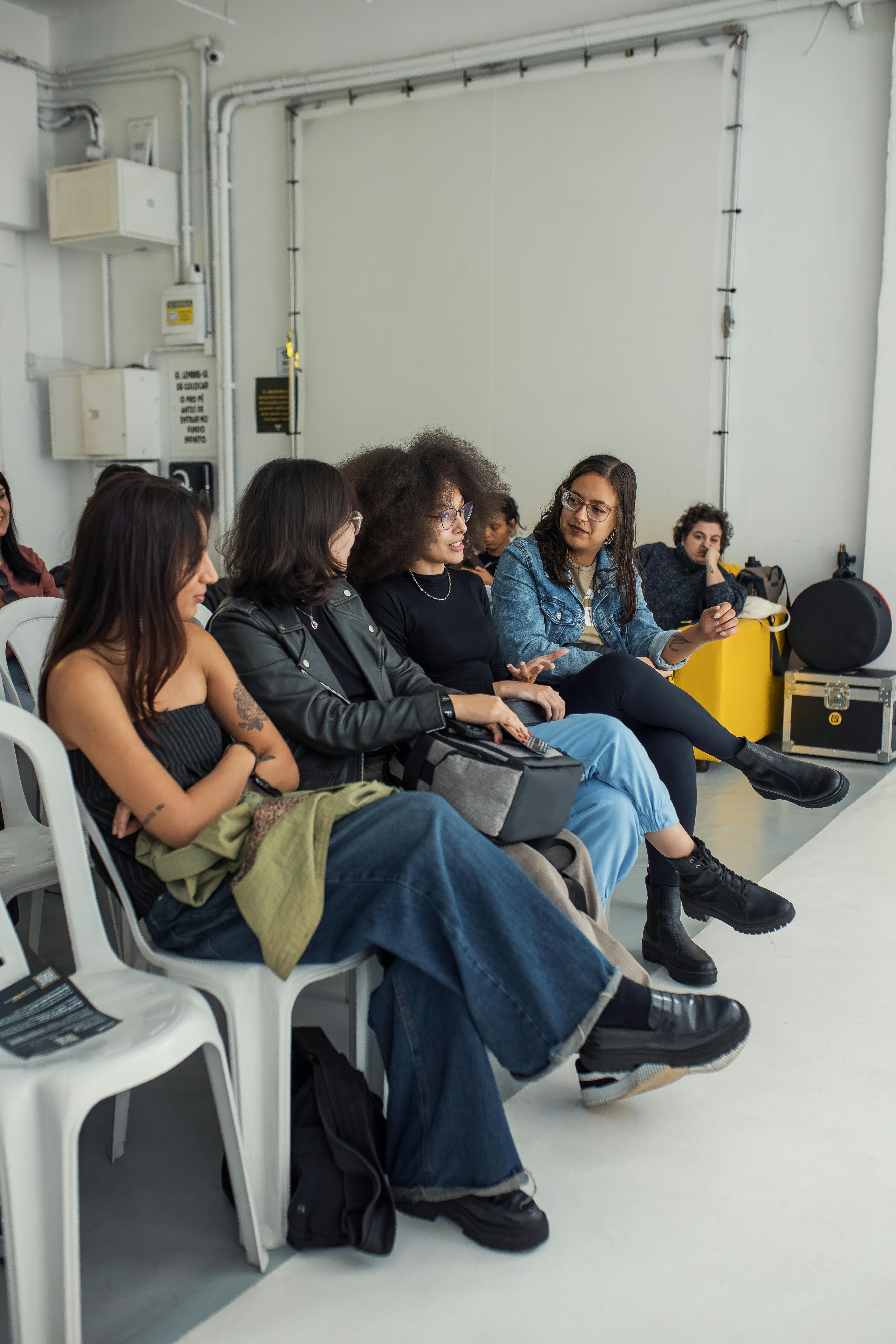 Group of young adults sitting and chatting at an indoor event, smiling and engaged.