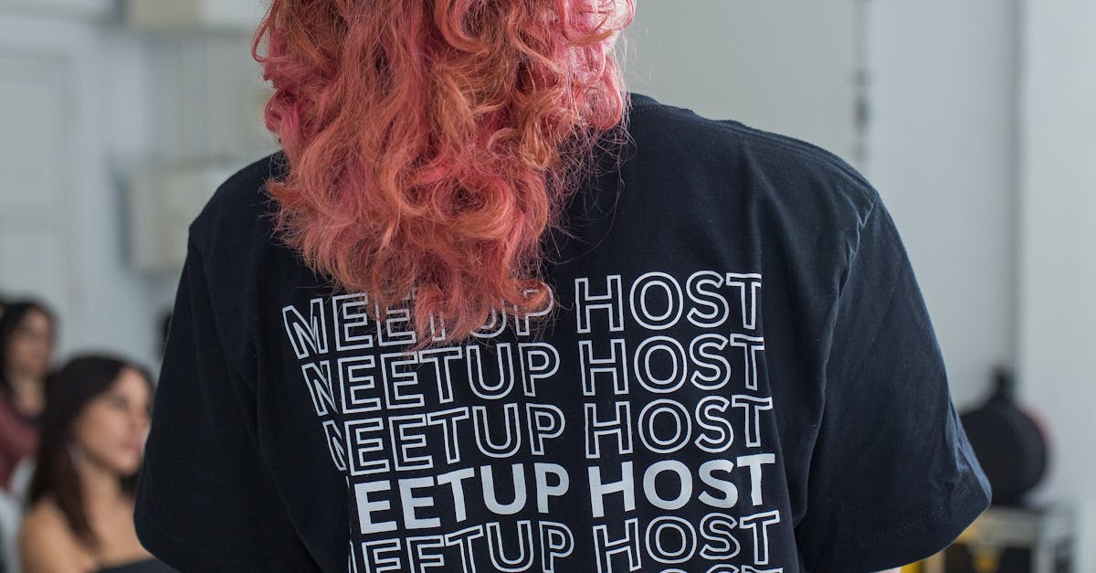 Woman with pink hair hosting a meetup event indoors, wearing a 'MEETUP HOST' shirt.