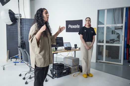 Two women in a photography studio with equipment and a Pexels banner.