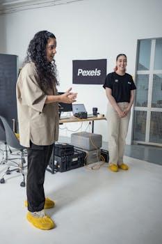 Two women in a modern office setting, wearing casual attire and yellow slippers.