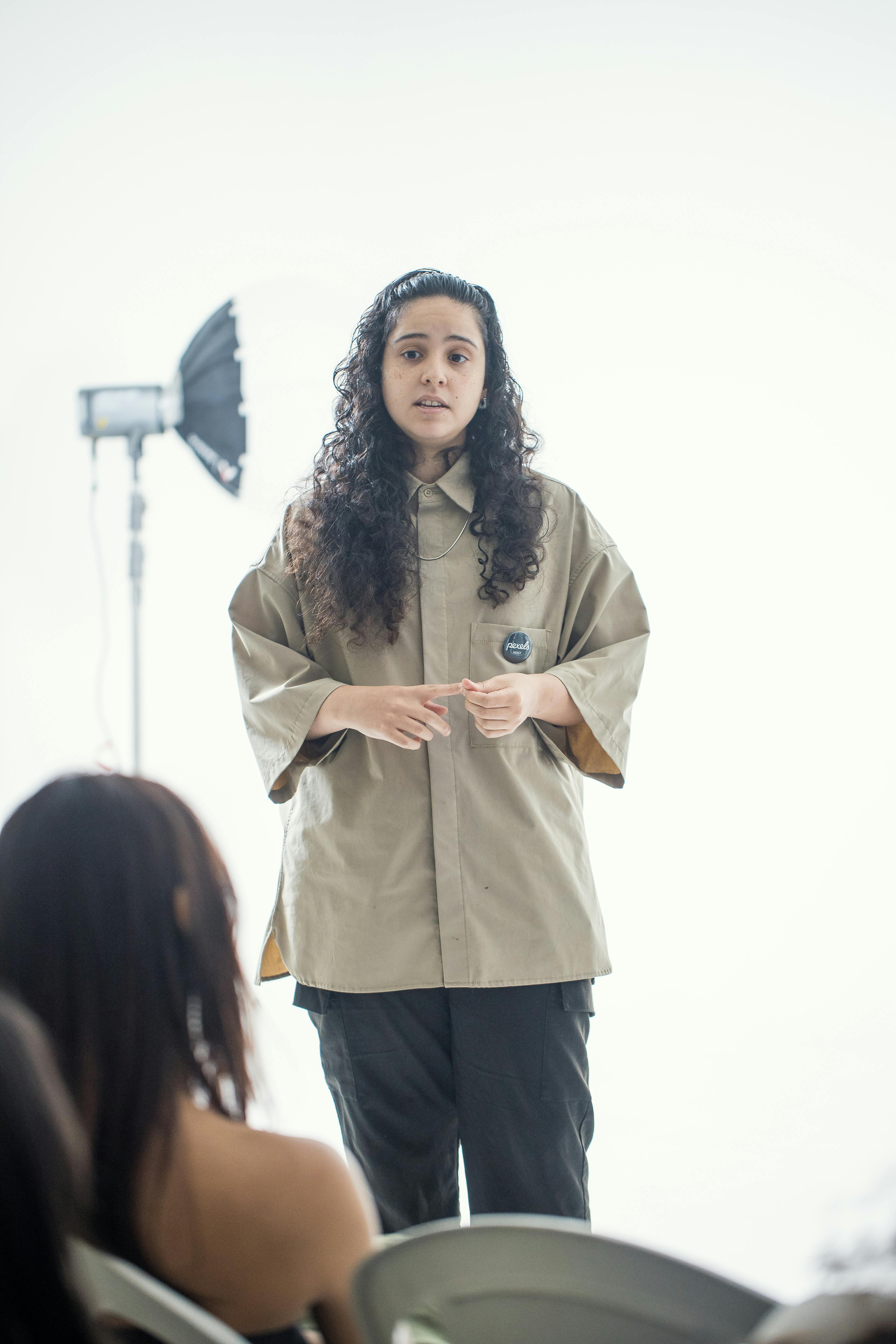 A woman speaks confidently in a well-lit studio, engaging her audience.