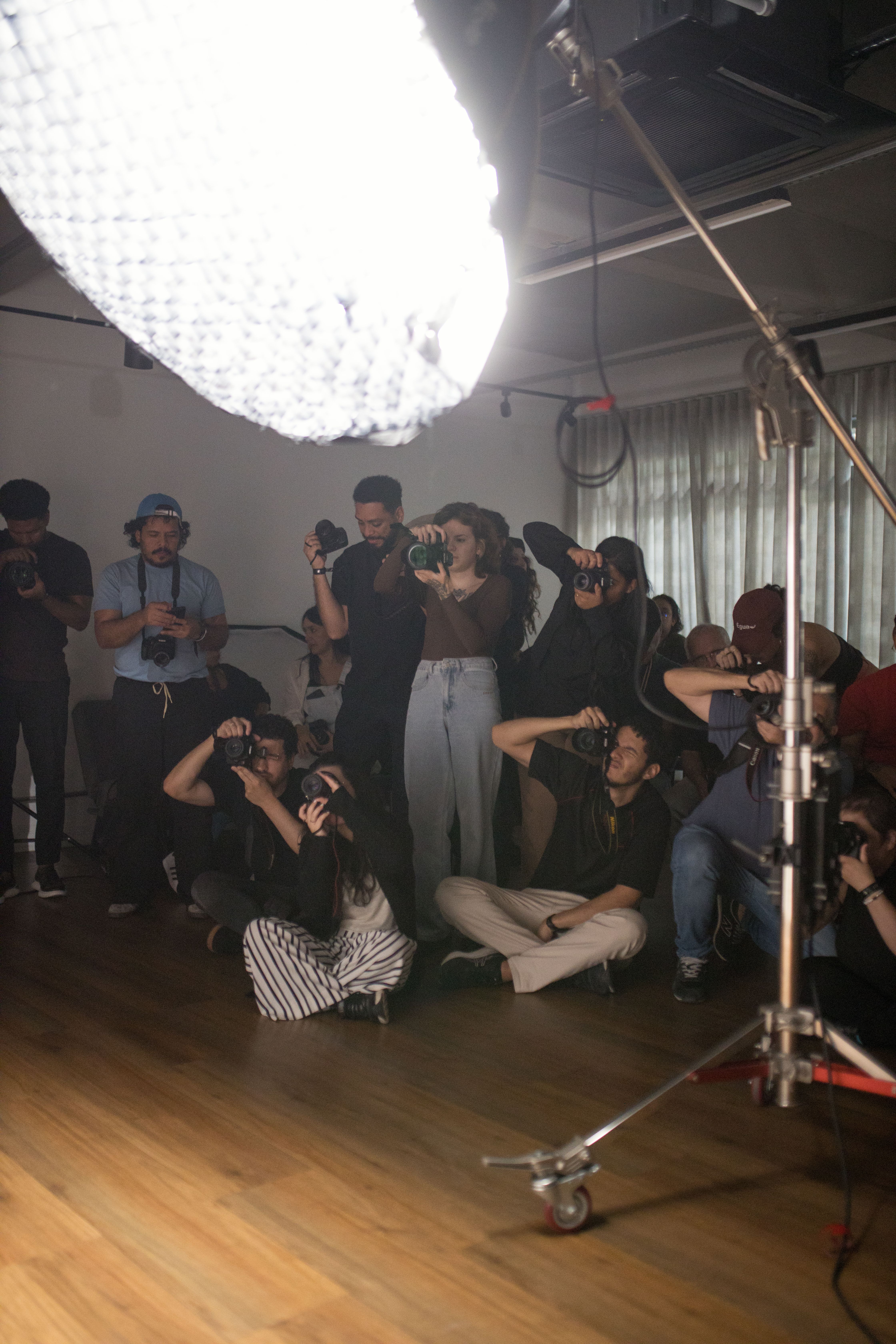 Group of photographers capturing images in a well-lit studio environment.