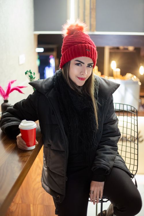 Free Stylish woman in a cafe wearing a red hat and enjoying a hot drink during winter. Stock Photo