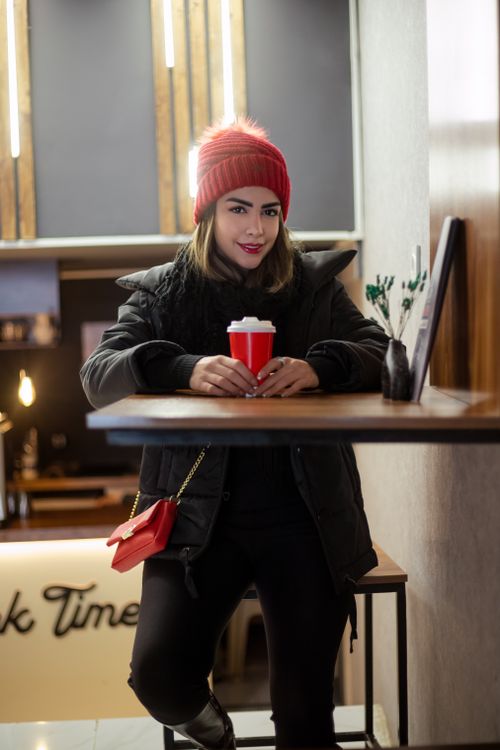 Free Stylish woman in winter attire enjoying coffee at a cozy indoor café table. Stock Photo