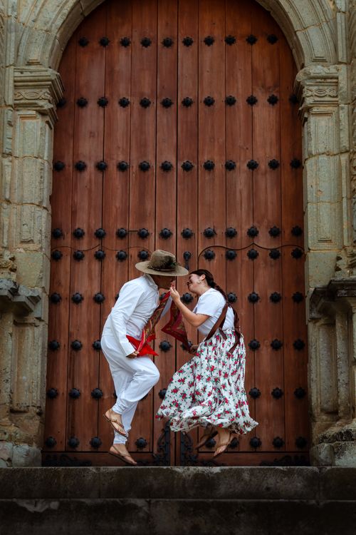 Free Couple dancing in traditional attire in front of historic church door in Oaxaca, Mexico. Stock Photo