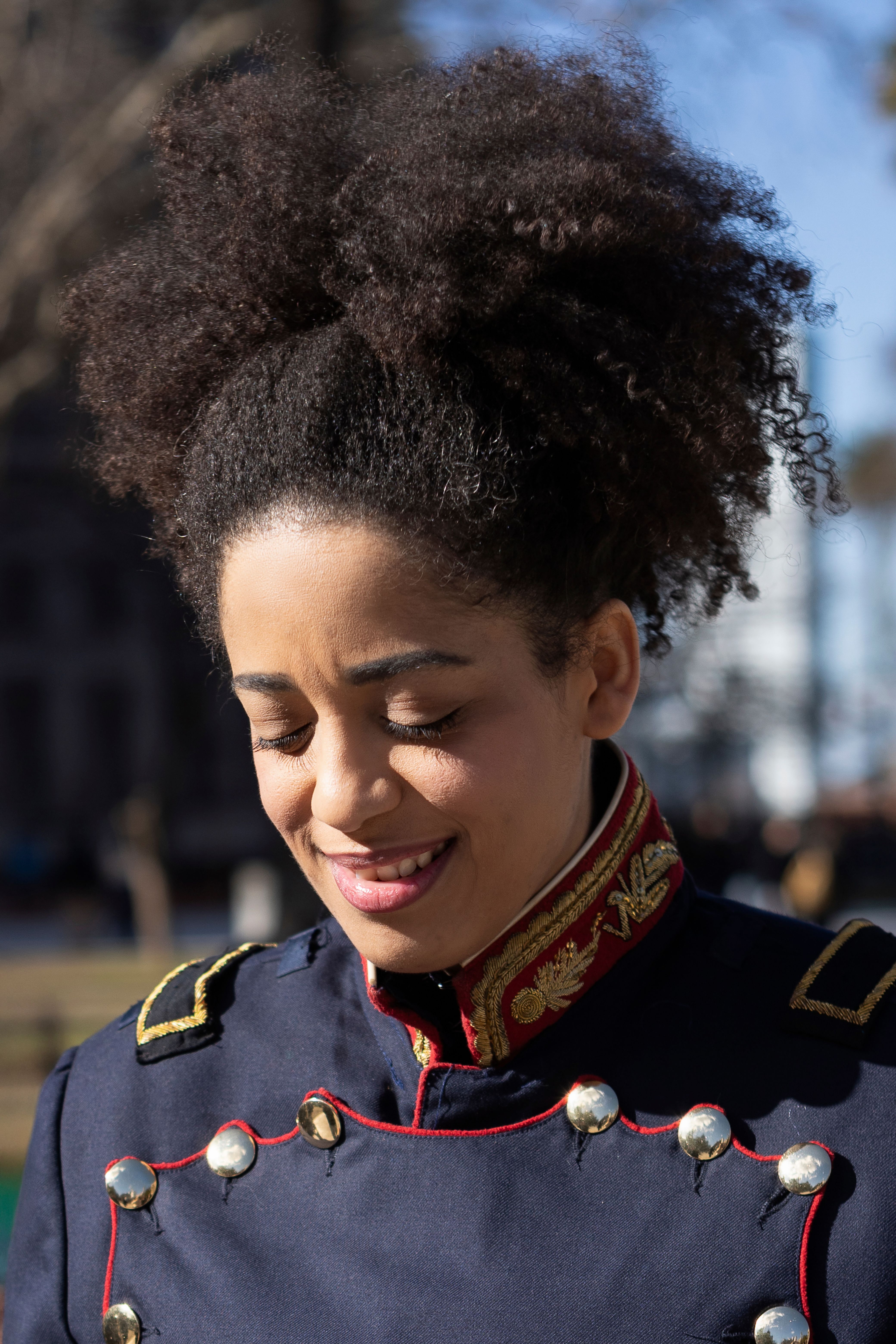 Smiling woman in ornate military-style uniform outdoors in Buenos Aires.