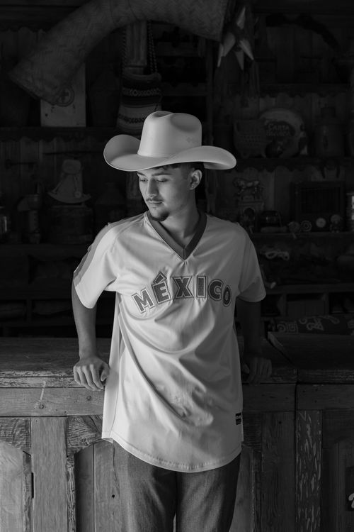 Free Black and white portrait of a young man in a cowboy hat with a Mexican jersey indoors. Stock Photo