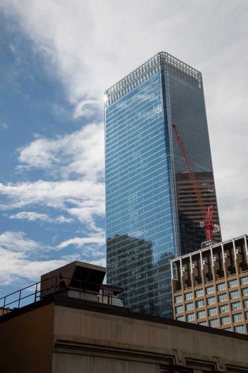 Free Modern skyscraper under construction in downtown Calgary, Canada with blue sky backdrop. Stock Photo