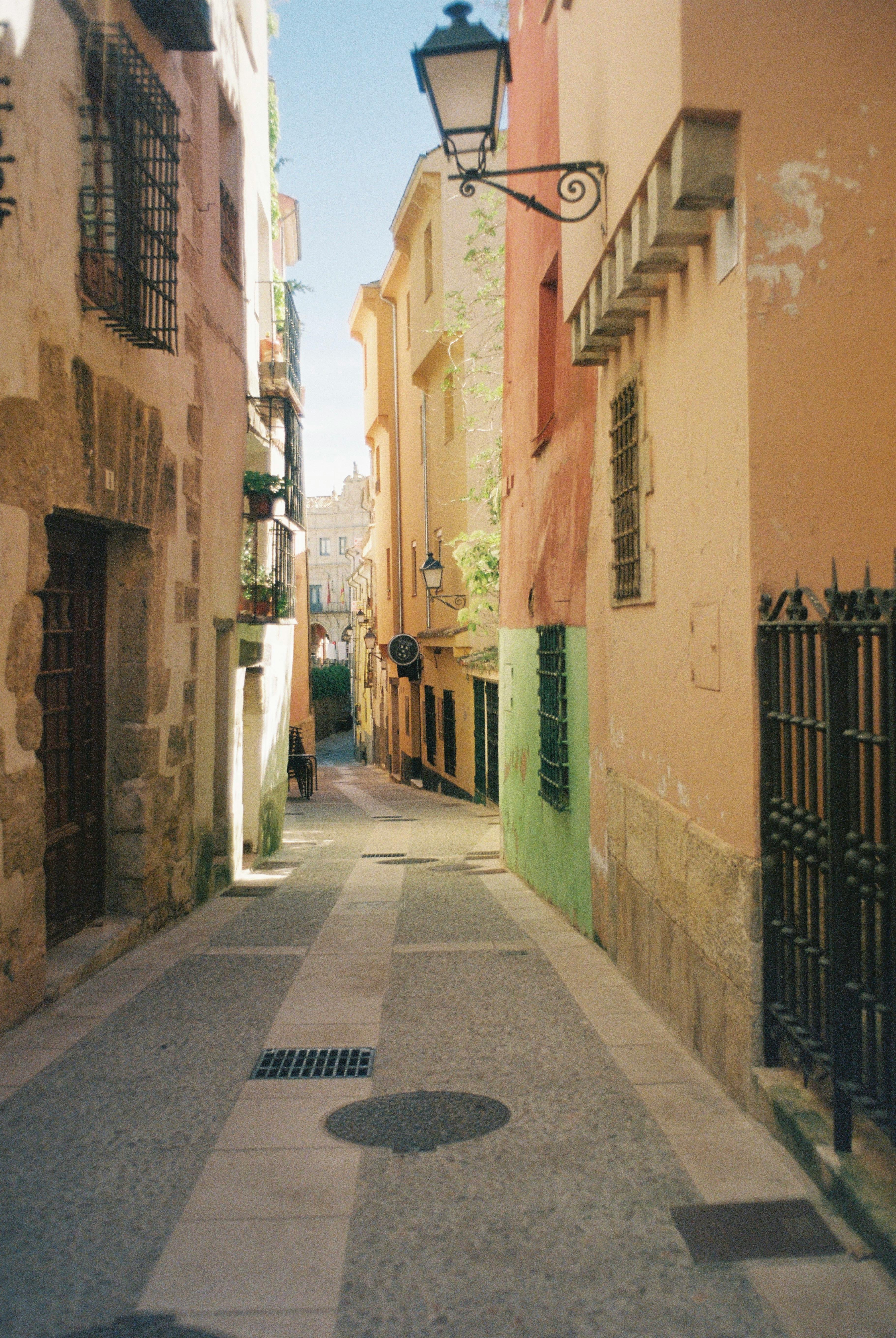 Picturesque alleyway in Cuenca, Spain highlighting colorful historic architecture.