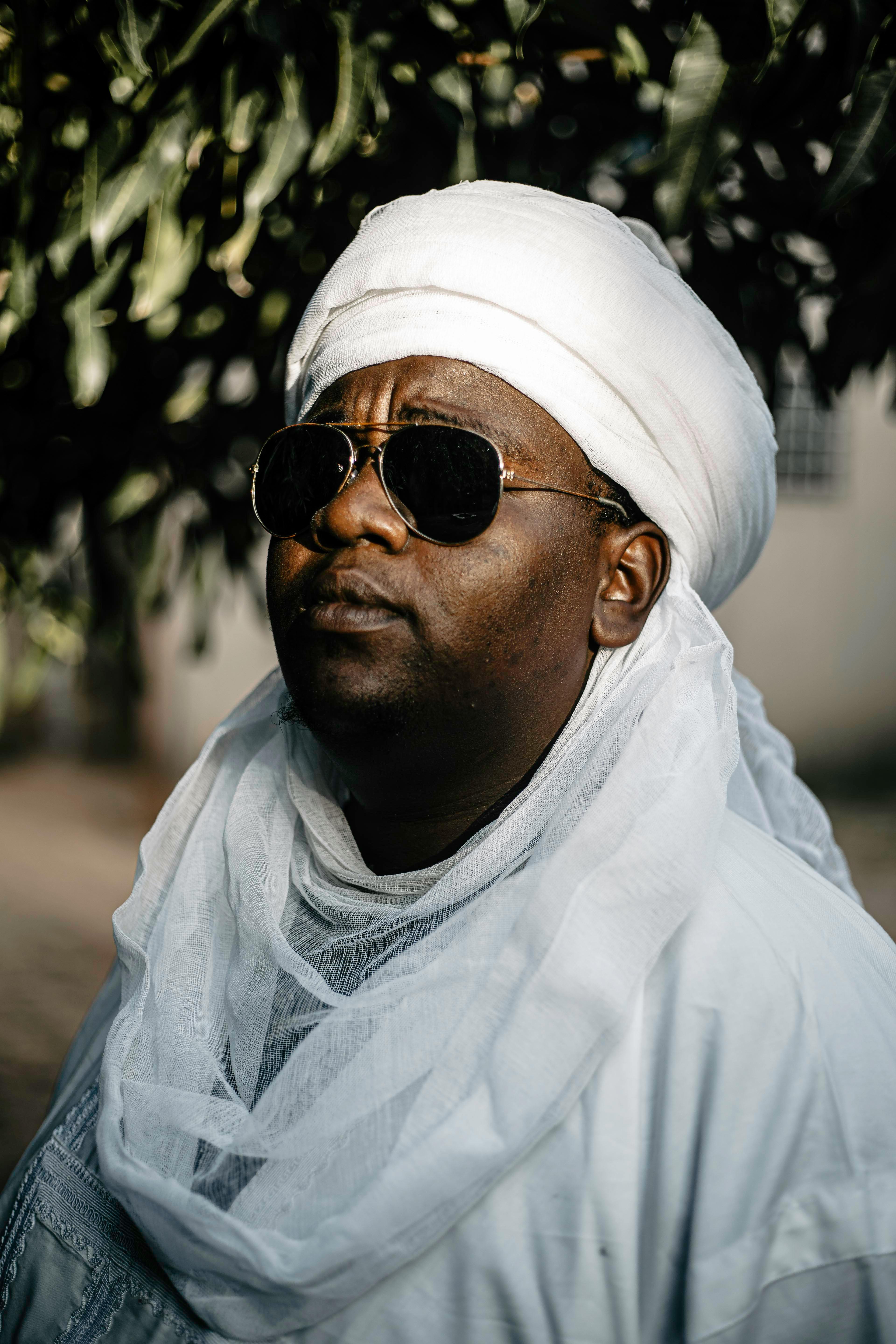 Portrait of a man in traditional Hausa attire wearing sunglasses in Daura, Nigeria.