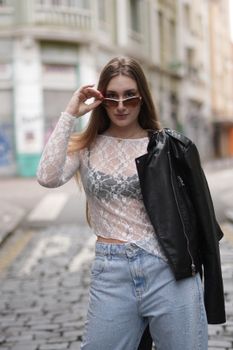 Stylish woman poses confidently on a cobblestone street in Curitiba, Brazil, showcasing modern fashion.