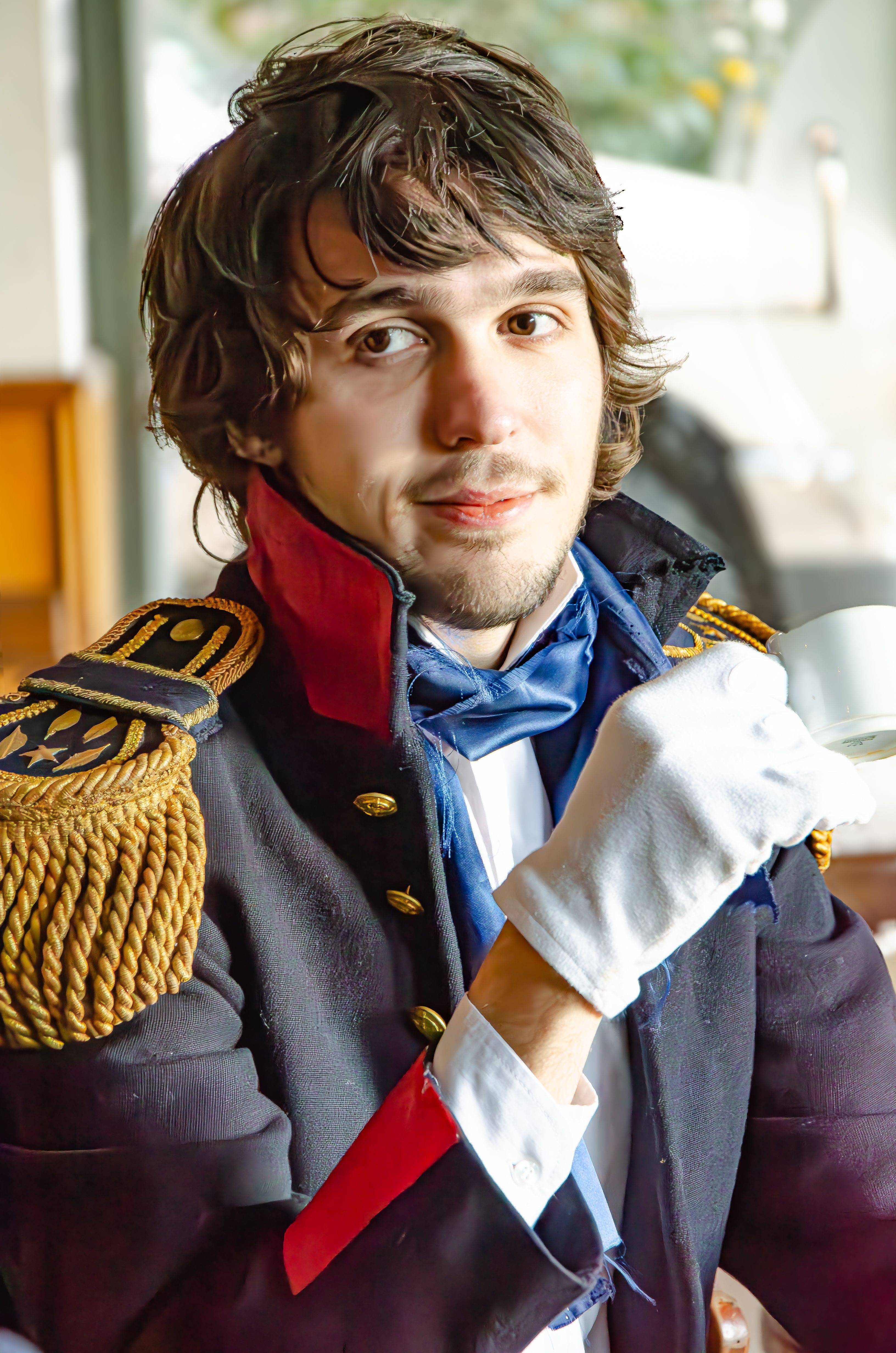 A man dressed in a historical military outfit sipping tea indoors in Buenos Aires.