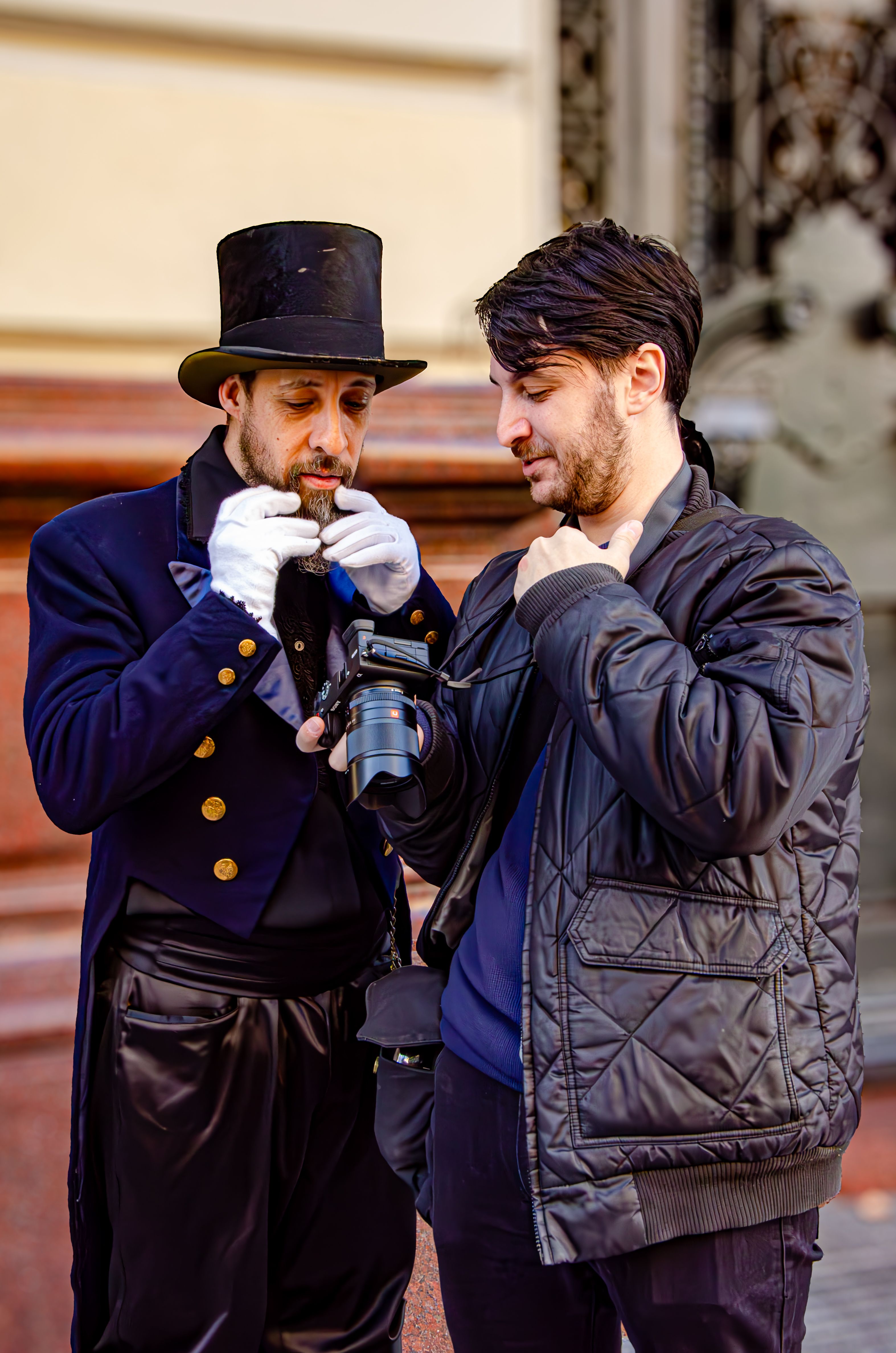 Street artist in top hat reviews photos with photographer in Buenos Aires.