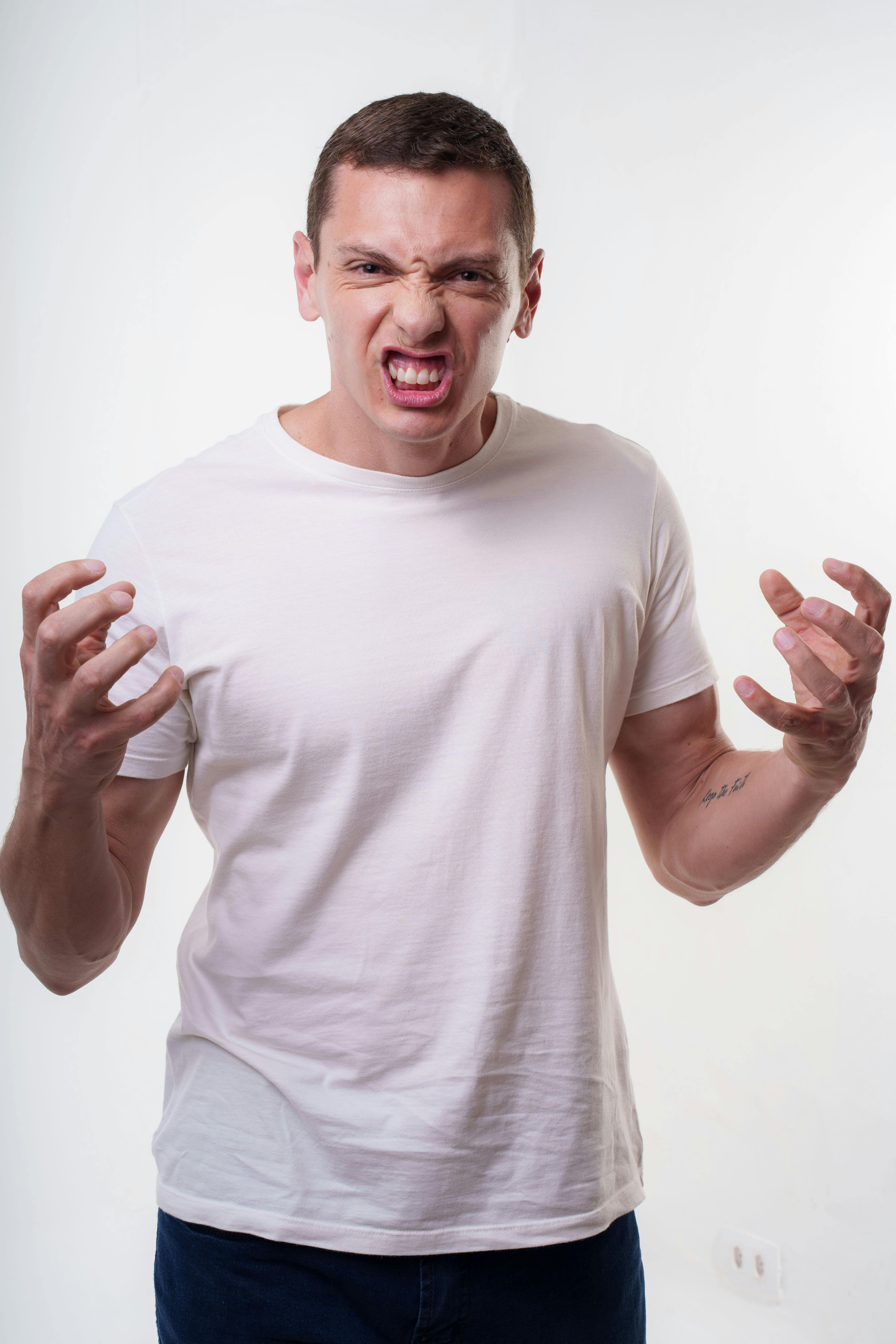 Angry young man clenching fists with a fierce expression. Studio portrait in Curitiba, Brazil.