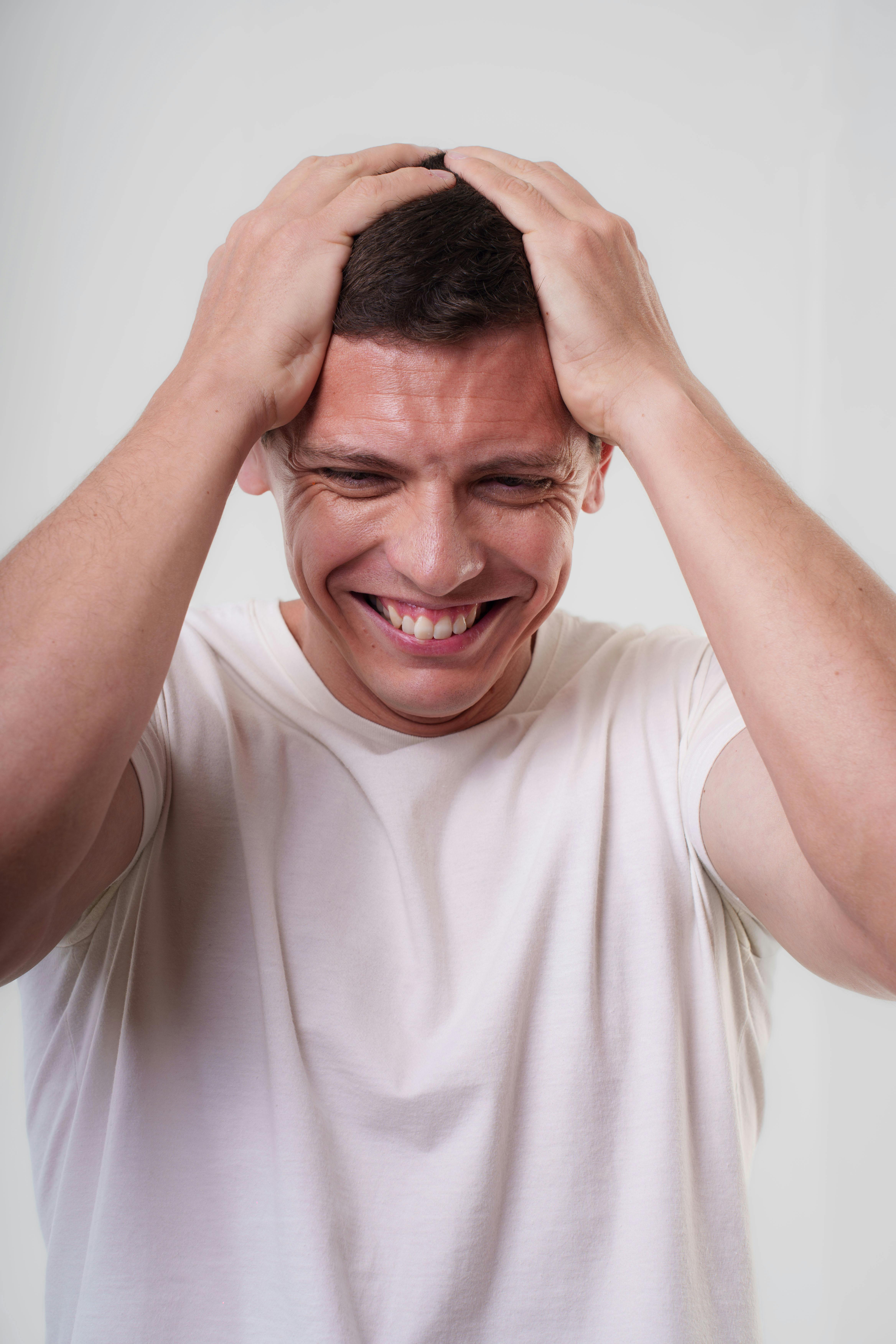 Free Portrait of a happy man smiling while holding his head, indoors. Stock Photo