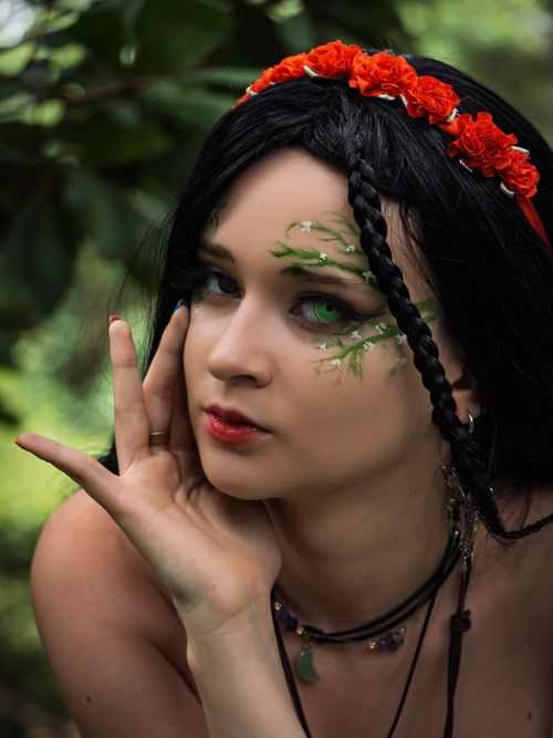 Free Artistic portrait of a woman with floral crown and makeup, set in lush green surroundings. Stock Photo