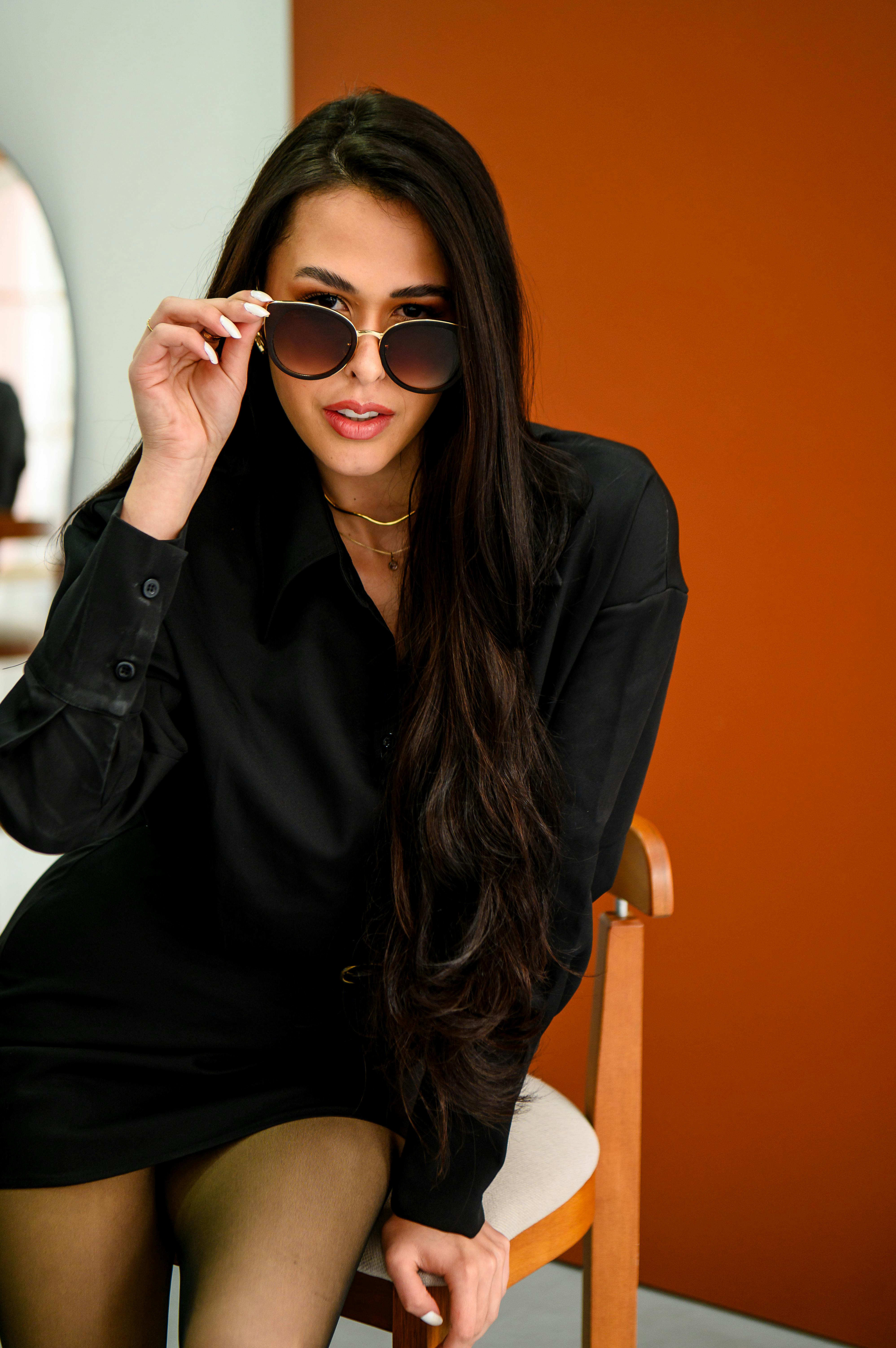 Bezpłatne Stylowa kobieta w okularach przeciwsłonecznych pozuje pewnie w nowoczesnym studiu. Zdjęcie z galerii